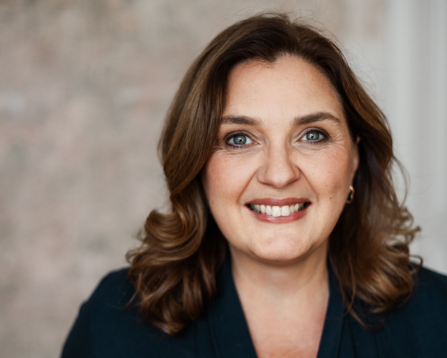 Woman wearing a dark blue top against a neutral background